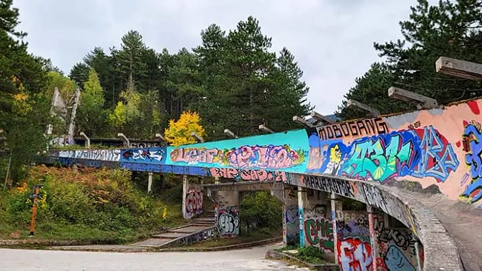 image of an abandoned bobsled track in the forest with colorful graffiti covering the concrete.