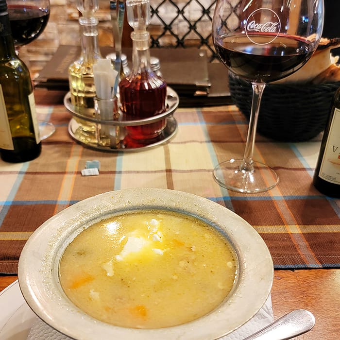 image of a silver bowl filled with chicken soup and a glass of wine with a Coca Cola logo