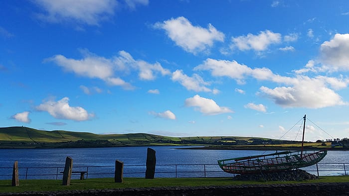 image from Dingle, Ireland, of a boat sculpture with the sea and green hills in the background