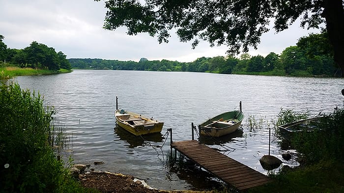 3_Denmark Road Trip image of small boats tied to a dock on a small lake surrounded by trees